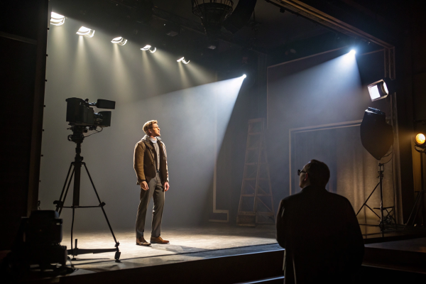 Actor on a lit stage with cameras, cinematic and theatrical production setup