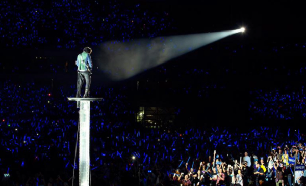 Spotlight focused on a performer, highlighting them against a dark audience background during a live concert